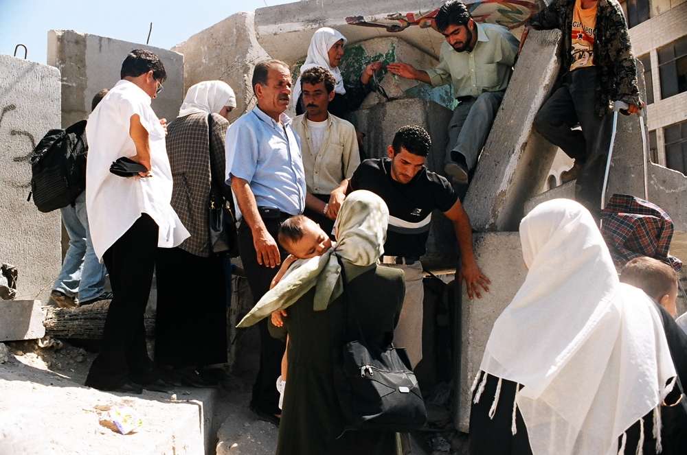Palestinian men crossing from Al-Azhariya through an opening in the concrete blocks at Adu Dis. Abu Dis, Sept.03 02