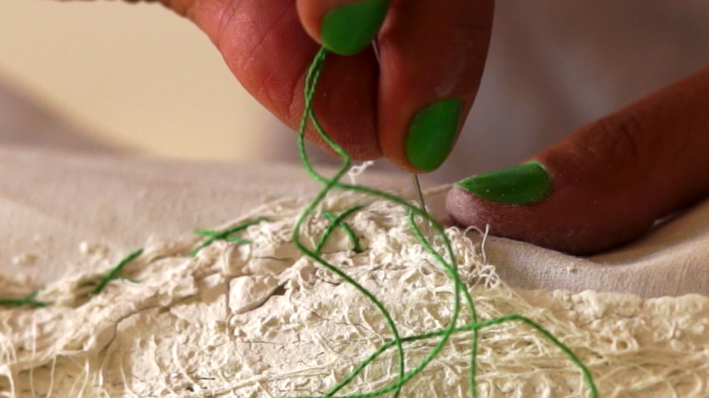 Sewing a green X on the wounded maps Sewing the map
